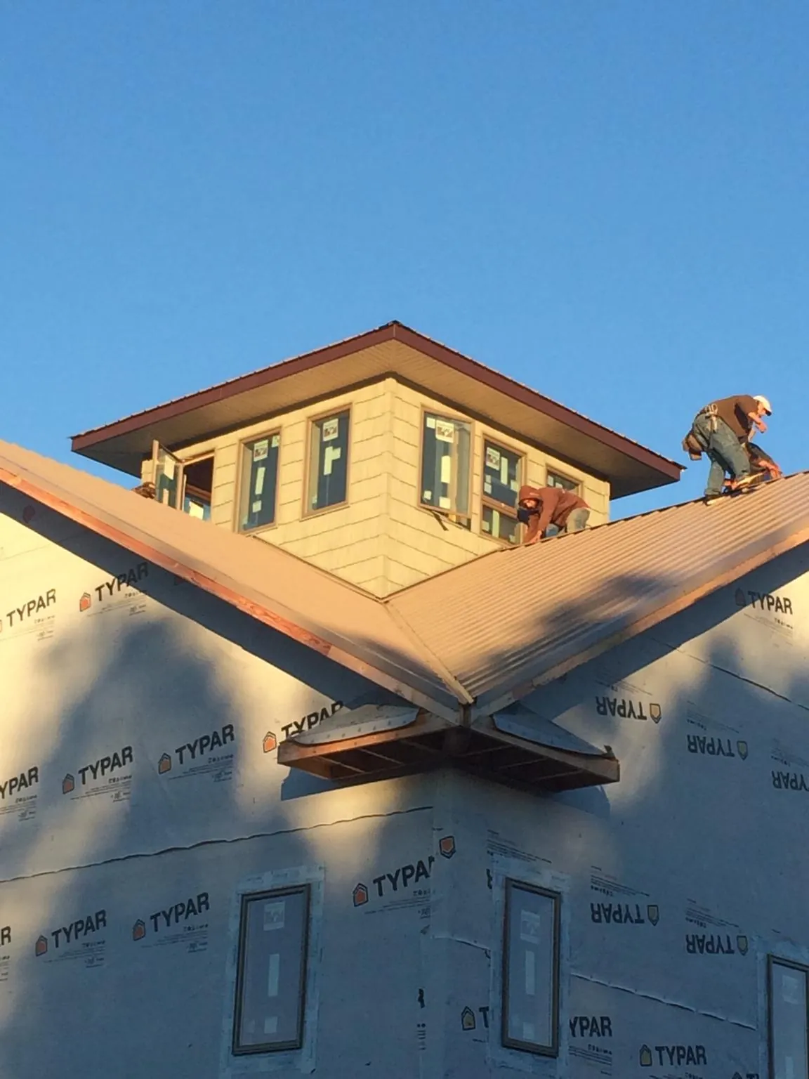 Roofers working around a rooftop cupola on a new metal roof at sunset — Roof Waterproofing in Canaan by Roofing Brothers